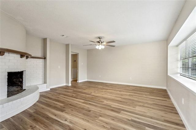 414 Pine Forest Dr, Slidell, LA 70458 - unfurnished living room with a brick fireplace, light wood-style flooring, ceiling fan, and baseboards