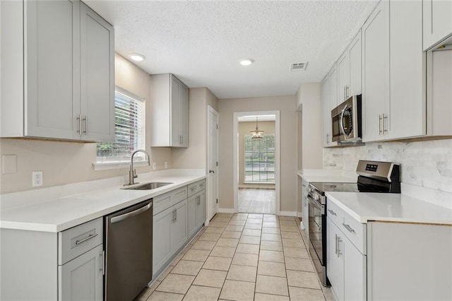 414 Pine Forest Dr, Slidell, LA 70458 - kitchen featuring stainless steel appliances, a sink, gray cabinetry, light countertops, and a textured ceiling