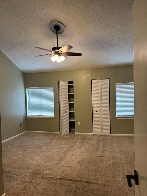 2836 Steamship Cir Unit A, River Ridge, LA 70123 - unfurnished bedroom featuring two closets, a textured ceiling, carpet, baseboards, and a ceiling fan