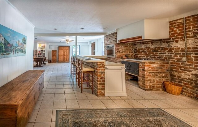 212 Linton Ave, Natchez-Ms, MS 39120 - kitchen with stainless steel oven, light tile patterned floors, a ceiling fan, a kitchen bar, and white cabinets