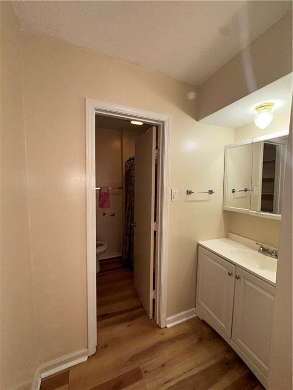 70915 S Gayoso St, New Orleans, LA 70119 - full bathroom featuring wood finished floors, vanity, toilet, and baseboards