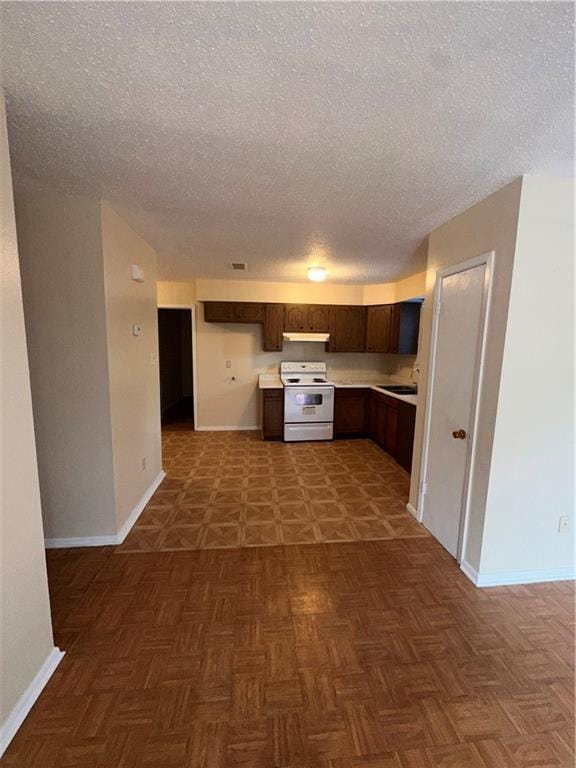 70915 S Gayoso St, New Orleans, LA 70119 - kitchen featuring white electric range, a textured ceiling, under cabinet range hood, baseboards, and light countertops