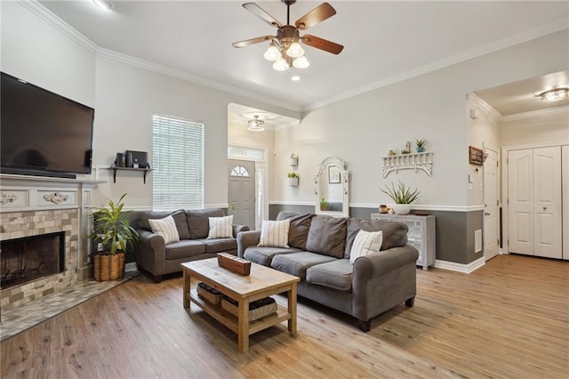 1400 Viola St, Mandeville, LA 70448 - living room featuring ceiling fan, light wood finished floors, crown molding, a fireplace with flush hearth, and baseboards
