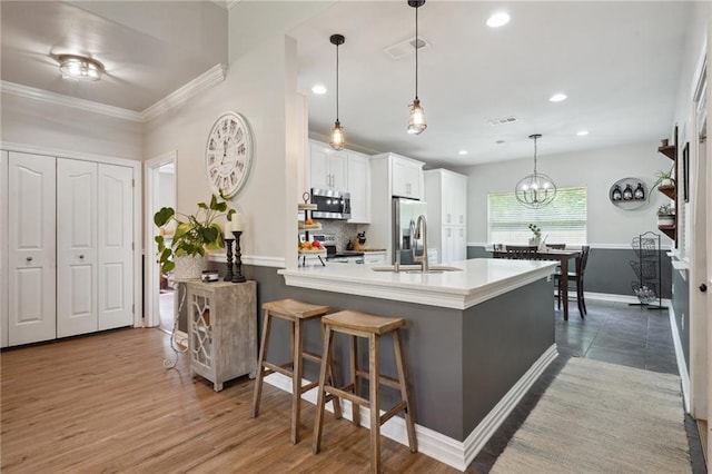 1400 Viola St, Mandeville, LA 70448 - kitchen with appliances with stainless steel finishes, a sink, a peninsula, white cabinetry, and a breakfast bar area