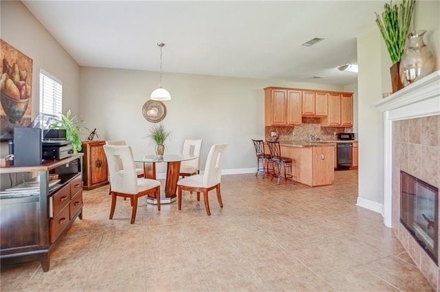39070 Pirogue Ave, Gonzales, LA 70737 - dining room featuring a tiled fireplace, baseboards, and light tile patterned floors