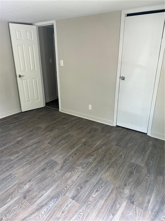 611 E Michigan St, Hammond, LA 70401 - unfurnished bedroom featuring dark wood-style flooring and baseboards