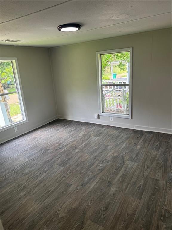 611 E Michigan St, Hammond, LA 70401 - empty room with dark wood finished floors, plenty of natural light, and baseboards