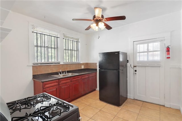 233537 Jasmine St, New Orleans, LA 70122 - kitchen with freestanding refrigerator, gas range, a sink, reddish brown cabinets, and healthy amount of natural light