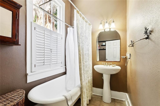 719 Atlantic Ave, New Orleans, LA 70114 - bathroom with tile patterned flooring, baseboards, a bathtub, a textured wall, and a shower with shower curtain