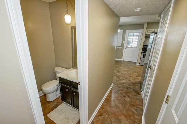 103 Omega St Unit B, Belle Chasse, LA 70037 - bathroom with toilet, vanity, baseboards, a textured ceiling, and tile patterned flooring
