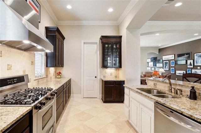 kitchen with appliances with stainless steel finishes, wall chimney range hood, a sink, backsplash, and light stone counters