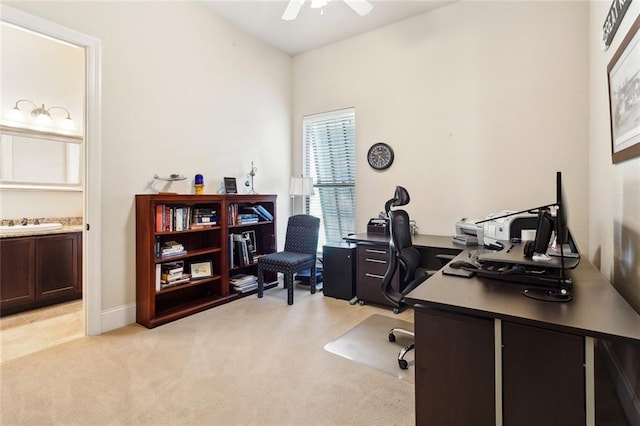 home office featuring a ceiling fan, light colored carpet, and baseboards