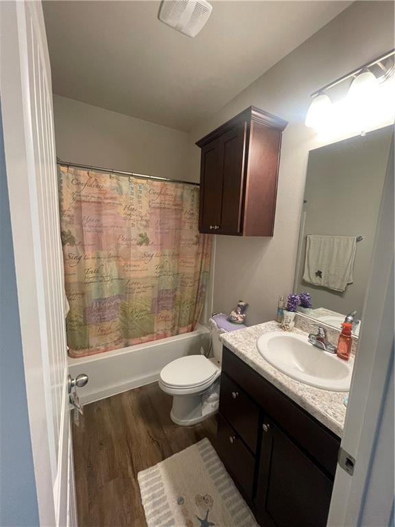 47715 Cathy Ln, Robert, LA 70455 - bathroom featuring vanity, wood finished floors, shower / bath combo with shower curtain, and toilet