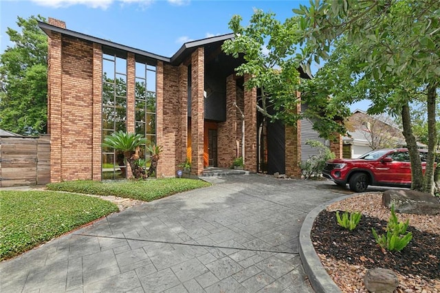3213 Tolmas Dr, Metairie, LA 70002 - view of front facade with brick siding, driveway, and a chimney
