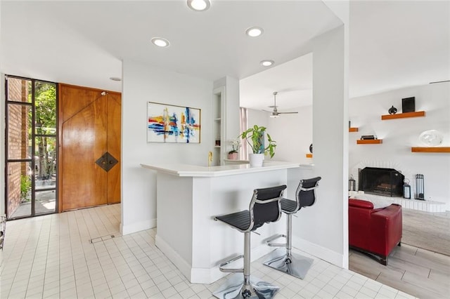 3213 Tolmas Dr, Metairie, LA 70002 - kitchen featuring a brick fireplace, recessed lighting, a kitchen breakfast bar, a ceiling fan, and light countertops