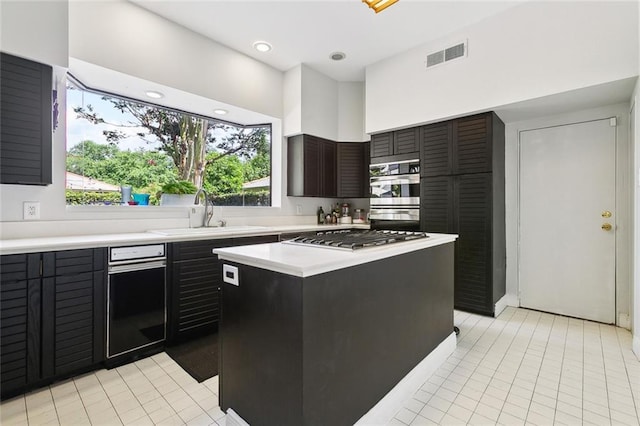 3213 Tolmas Dr, Metairie, LA 70002 - kitchen featuring appliances with stainless steel finishes, a sink, light countertops, light tile patterned flooring, and a kitchen island
