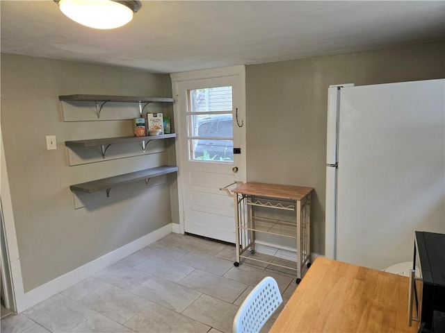 1222 Broadway St, New Orleans, LA 70118 - kitchen with freestanding refrigerator, baseboards, and light tile patterned floors