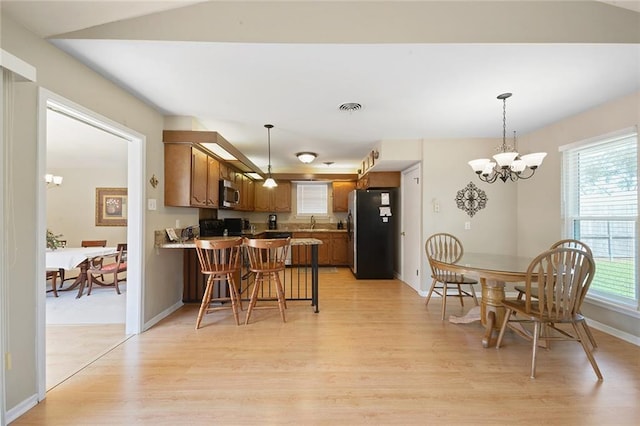 5705 Lafreniere St, Metairie, LA 70003 - kitchen featuring stainless steel appliances, a chandelier, light wood finished floors, a peninsula, and brown cabinetry