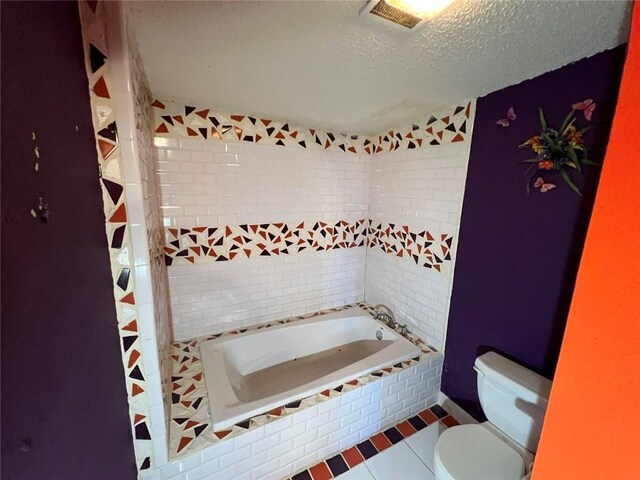 320 De Armas St, New Orleans, LA 70114 - bathroom with tiled tub, toilet, a textured ceiling, and tile patterned flooring
