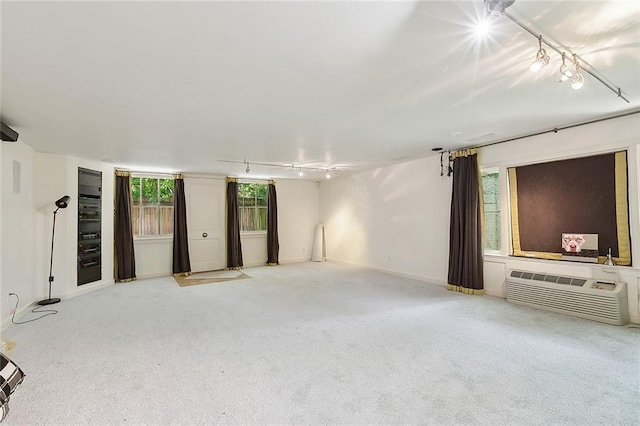 1633 Dufossat St, New Orleans, LA 70115 - unfurnished living room with rail lighting, an AC wall unit, carpet flooring, and baseboards