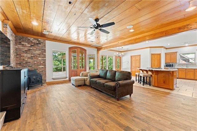 25766 La Highway 1032, Denham Springs, LA 70726 - living room featuring wood ceiling, a wood stove, ornamental molding, light wood-style floors, and plenty of natural light