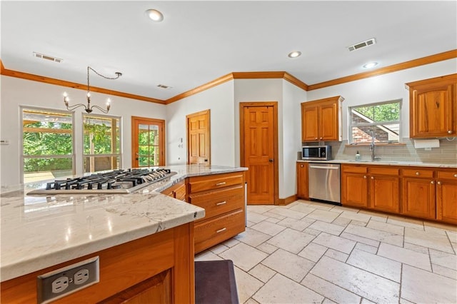 25766 La Highway 1032, Denham Springs, LA 70726 - kitchen featuring appliances with stainless steel finishes, a sink, decorative backsplash, brown cabinets, and plenty of natural light