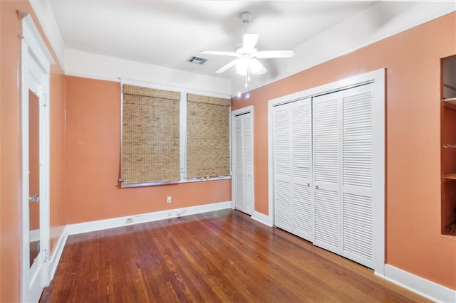2622 Wisteria St, New Orleans, LA 70122 - unfurnished bedroom featuring two closets, wood finished floors, baseboards, and ceiling fan