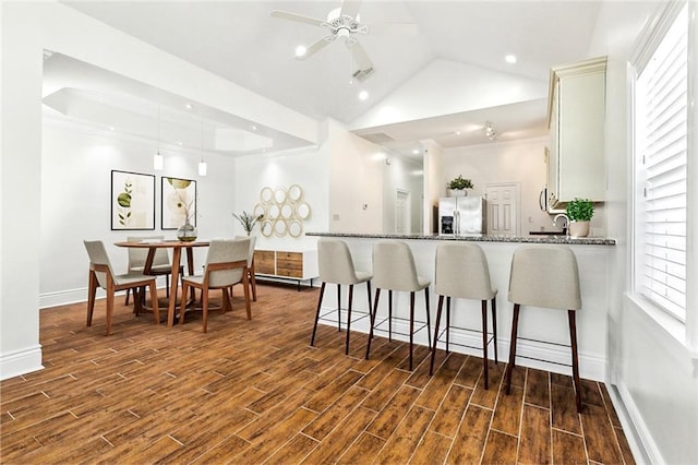 3316 Calhoun St, New Orleans, LA 70125 - kitchen featuring stainless steel refrigerator with ice dispenser, dark wood-style flooring, a ceiling fan, a kitchen bar, and vaulted ceiling