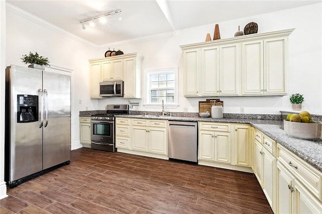 3316 Calhoun St, New Orleans, LA 70125 - kitchen featuring stainless steel appliances, cream cabinetry, track lighting, a sink, and dark stone counters