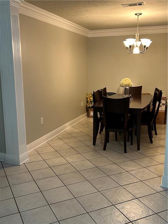 1705 Armagh Dr, Marrero, LA 70072 - dining area featuring crown molding, light tile patterned floors, a chandelier, and baseboards