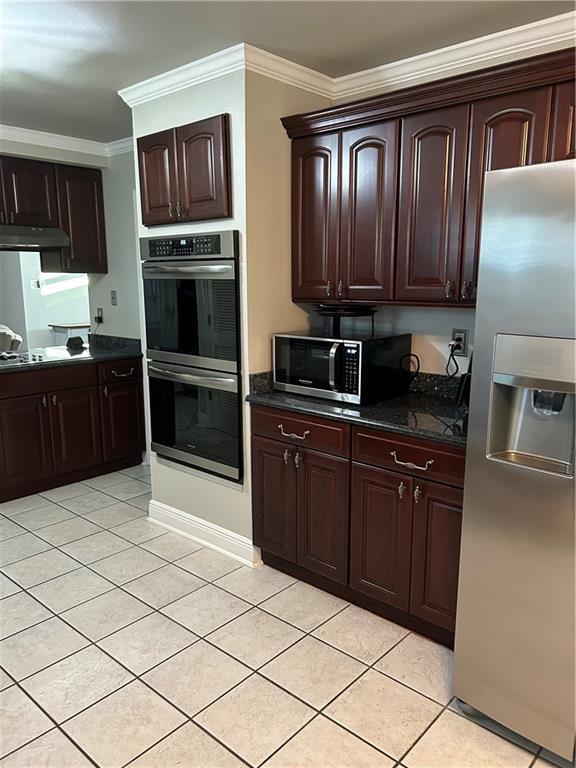 1705 Armagh Dr, Marrero, LA 70072 - kitchen with appliances with stainless steel finishes, under cabinet range hood, ornamental molding, light tile patterned flooring, and dark brown cabinetry