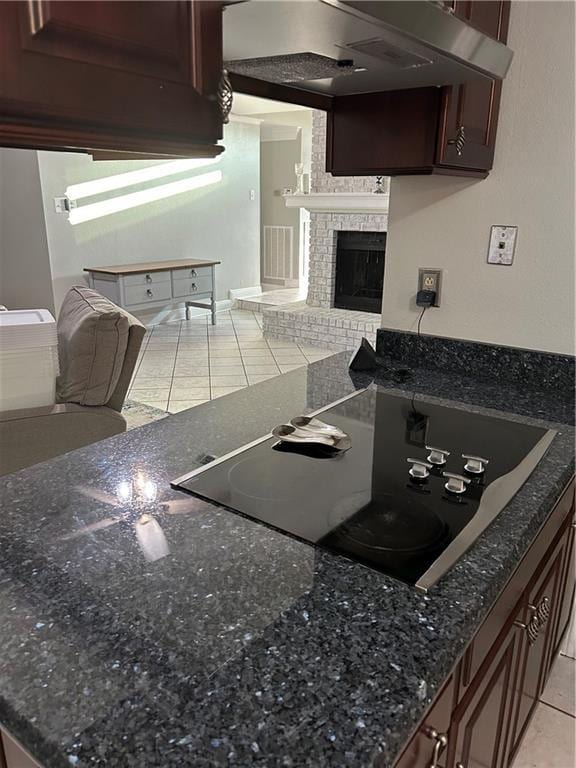 1705 Armagh Dr, Marrero, LA 70072 - kitchen featuring black electric stovetop, open floor plan, light tile patterned floors, a fireplace, and dark stone countertops