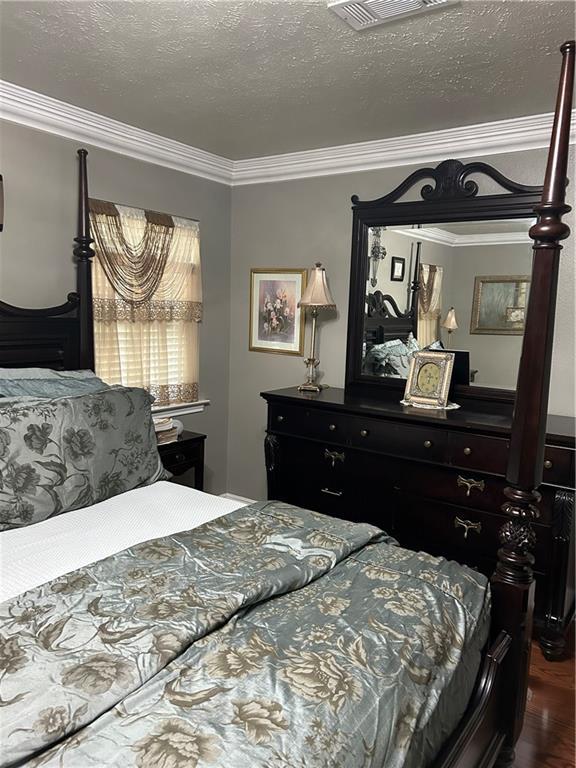1705 Armagh Dr, Marrero, LA 70072 - bedroom featuring crown molding, dark wood finished floors, and a textured ceiling