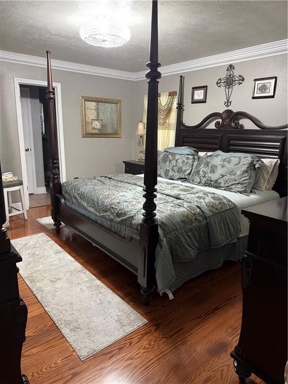 1705 Armagh Dr, Marrero, LA 70072 - bedroom with crown molding, a textured ceiling, and wood finished floors