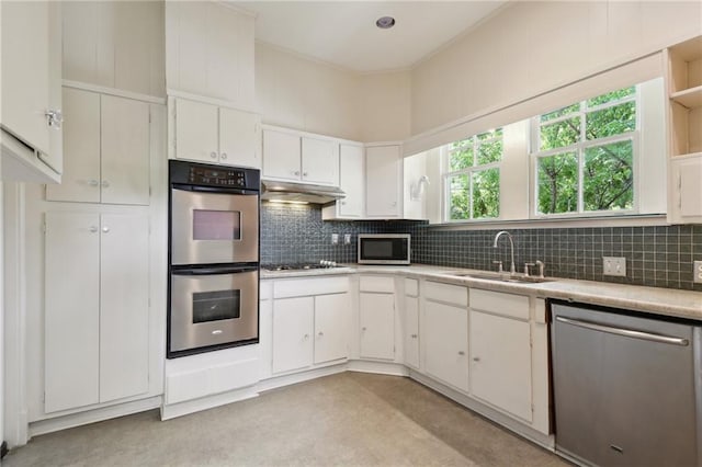 1665 Dufossat St, New Orleans, LA 70115 - kitchen with appliances with stainless steel finishes, a sink, under cabinet range hood, light countertops, and white cabinets