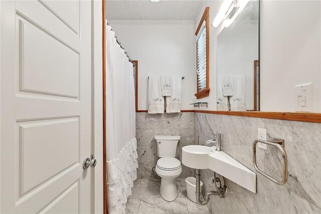 602 Jefferson Ave, New Orleans, LA 70115 - bathroom featuring toilet, tile walls, tile patterned floors, a shower with curtain, and a wainscoted wall