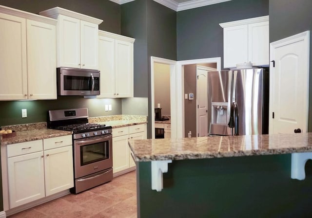 43357 Quiet Lake Dr, Hammond, LA 70403 - kitchen with stainless steel appliances, a kitchen breakfast bar, ornamental molding, light stone counters, and white cabinetry