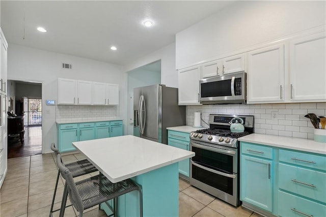 6118 Canal Blvd, New Orleans, LA 70124 - kitchen featuring appliances with stainless steel finishes, blue cabinetry, a breakfast bar area, light tile patterned floors, and white cabinets