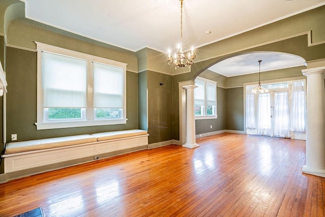 606 Filmore St, New Orleans, LA 70124 - spare room featuring decorative columns, arched walkways, light wood finished floors, a chandelier, and crown molding