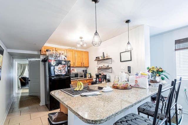 606 Filmore St, New Orleans, LA 70124 - kitchen with freestanding refrigerator, a kitchen bar, light tile patterned floors, hanging light fixtures, and baseboards