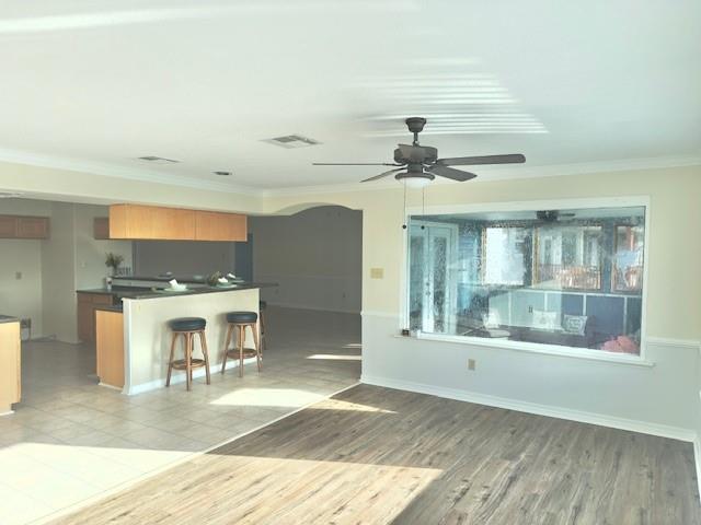 4231 San Trovaso St, New Orleans, LA 70129 - kitchen with a ceiling fan, arched walkways, ornamental molding, dark countertops, and a breakfast bar
