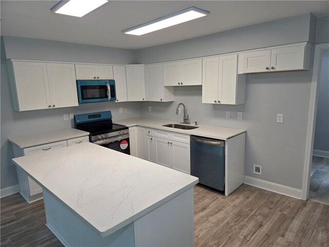 59478 S Tranquility Rd, Lacombe, LA 70445 - kitchen featuring appliances with stainless steel finishes, a sink, baseboards, wood finished floors, and white cabinets