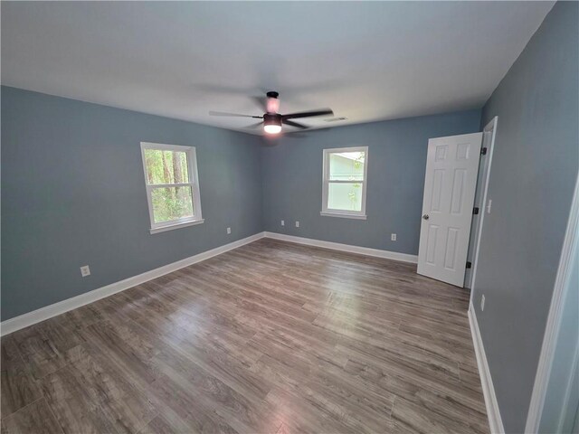 59478 S Tranquility Rd, Lacombe, LA 70445 - unfurnished bedroom with multiple windows, baseboards, wood finished floors, and a ceiling fan