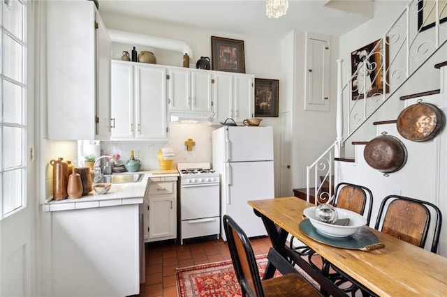 927 Dauphine St, New Orleans, LA 70116 - kitchen featuring white appliances, white cabinetry, a sink, under cabinet range hood, and brick flooring
