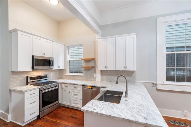 82729 Mazant St, New Orleans, LA 70117 - kitchen featuring appliances with stainless steel finishes, a sink, a peninsula, backsplash, and white cabinets