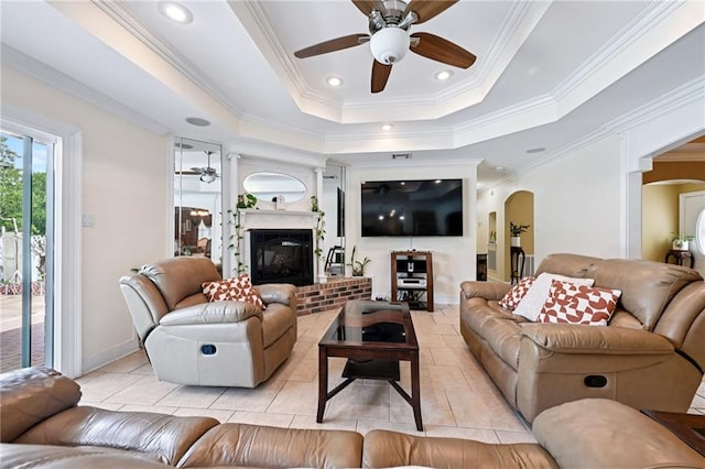 581 S Military Rd, Slidell, LA 70461 - living room with a ceiling fan, arched walkways, light tile patterned flooring, a tray ceiling, and a brick fireplace