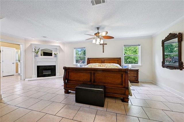 581 S Military Rd, Slidell, LA 70461 - bedroom featuring crown molding, multiple windows, light tile patterned flooring, a glass covered fireplace, and a textured ceiling