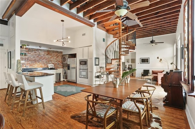 4716 Annunciation St Unit 3A, New Orleans, LA 70115 - dining area featuring ceiling fan, stacked washer / drying machine, stairs, a high ceiling, and wood finished floors