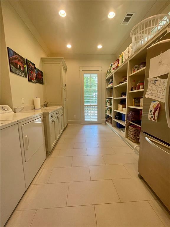 607 E 3rd Ave, Covington, LA 70433 - laundry area with washing machine and clothes dryer, ornamental molding, recessed lighting, light tile patterned flooring, and baseboards