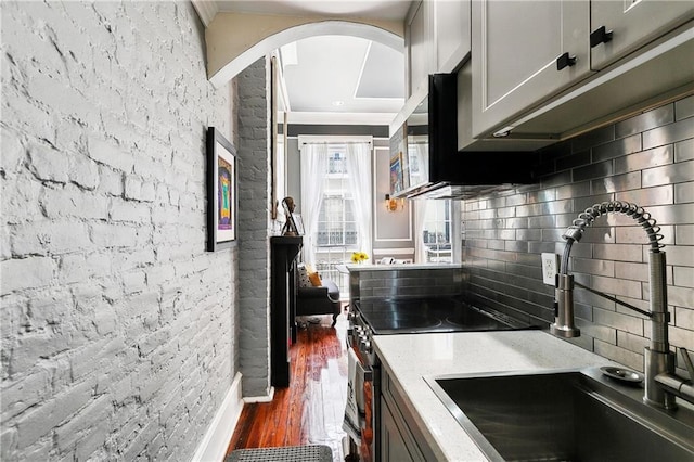 827 Burgundy St Unit C, New Orleans, LA 70116 - kitchen with a sink, tasteful backsplash, crown molding, arched walkways, and dark wood-style flooring